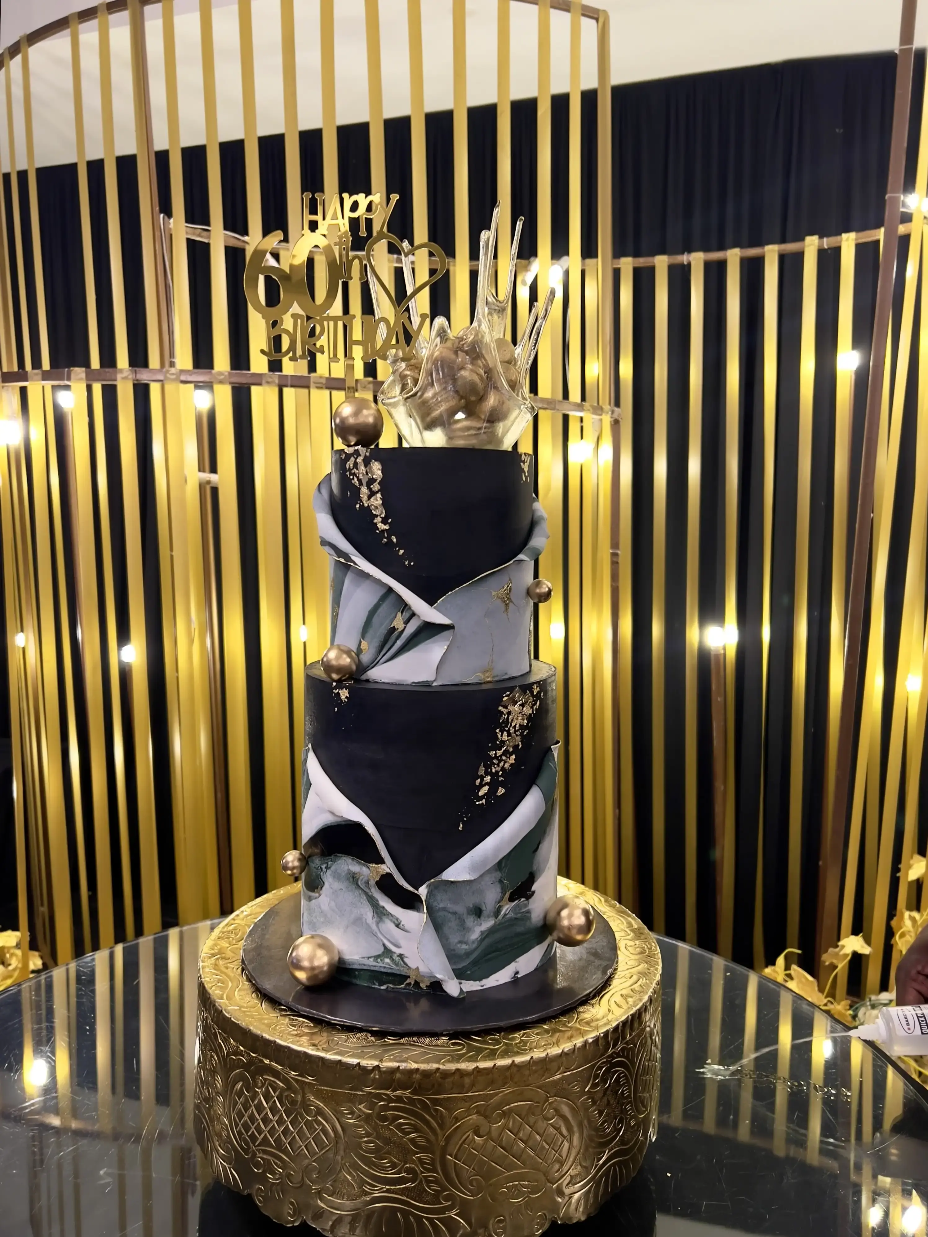 Black and grey marble two-tier cake with gold leaf and a glass-shard topper